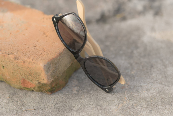 Klassieke zonnebril model met zwarte lenzen schieten in creatieve outdoor plaats close-up. Selectieve focus - Foto, afbeelding