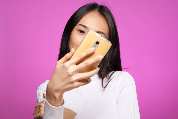 hezká brunetka s telefonem v ruce chatování internet online růžové pozadí - Fotografie, Obrázek