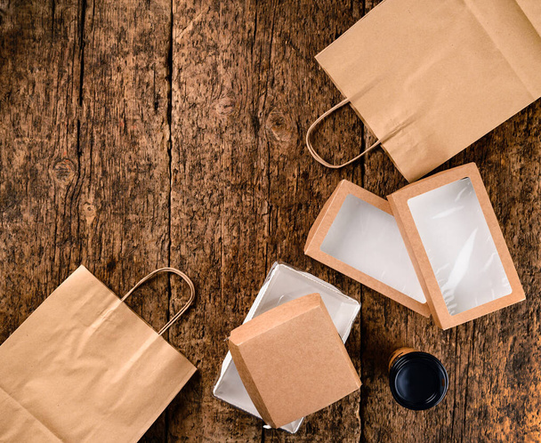 Eco craft paper tableware. Paper cups, dishes, bag, fast food containers, box for delivery food. Recycling concept. Zero waste. eco friendly food delivery boxes on wooden background with copy space - Fotografie, Obrázek
