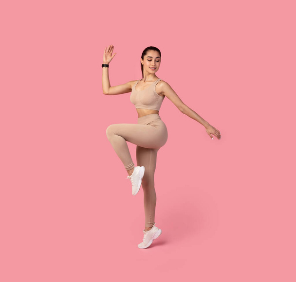 Sportos nő csinál magas térdek Gyakorlat elszigetelt rózsaszín háttér - Fotó, kép