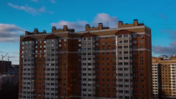 Timelapse - appartementencomplex tegen blauwe lucht met snel bewegende witte wolken - Video