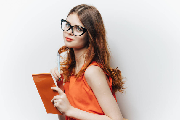 mujer pelirroja en camisa con bloc de notas gafas encanto moda fondo claro - Foto, Imagen