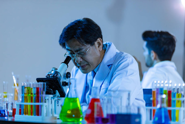 Mikrobiolog biotechnologický vědec nebo zdravotnický pracovník tým podívat mikroskop v laboratoři pro výzkum chemických dat asijských vědců. - Fotografie, Obrázek