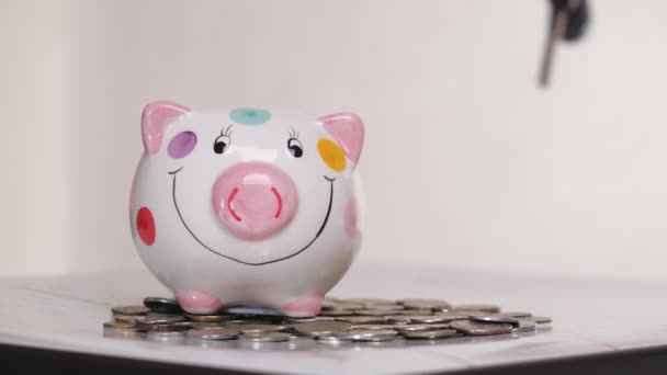 Das Sparschweingeschäft steht auf einem Haufen Münzen. Eine Hand steckt eine Münze in ein Lifestyle-Sparschwein auf gelbem Hintergrund. Geld zu sparen ist eine Investition in die Zukunft. Bankeninvestitionen. - Filmmaterial, Video