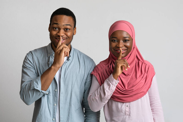 Muzułmańskie czarne pary zrobić znak milczenia, trzymać palce wskazujące na ustach - Zdjęcie, obraz