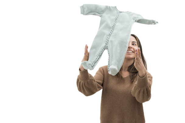 Νεαρή γυναίκα με τεντωμένα χέρια πετάει μωρουδιακά ρούχα στον αέρα - Φωτογραφία, εικόνα