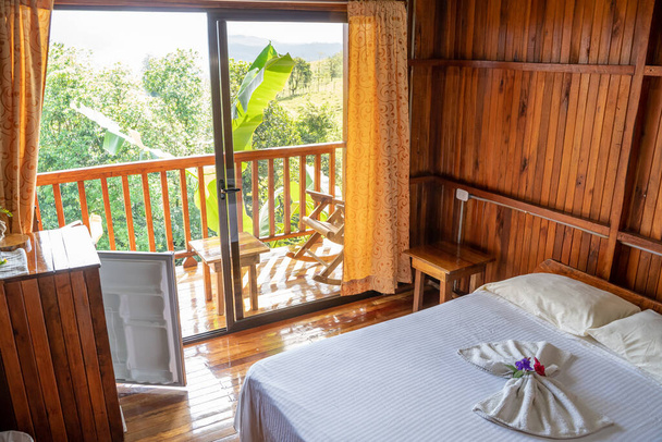 Rustikální hotelový pokoj s terasou se závěsy a ručníky složenými na lůžkách - Fotografie, Obrázek
