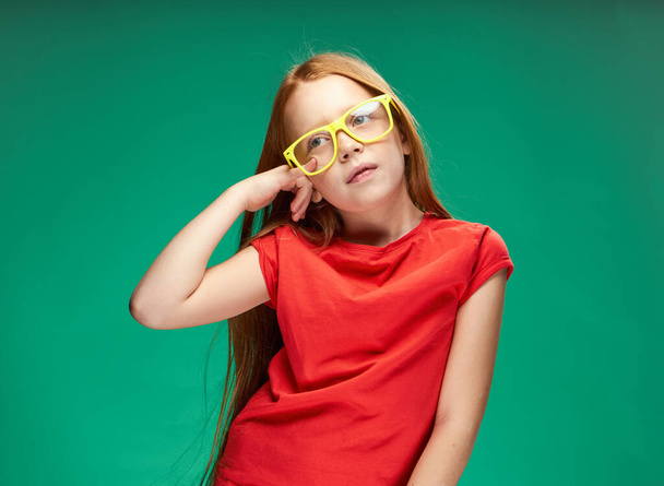 linda chica de pelo rojo gesto con sus manos infancia verde fondo escuela - Foto, imagen