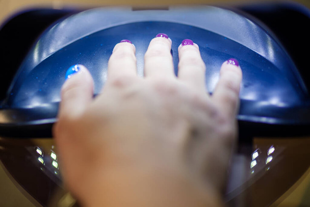 Detailní záběr ženy ruku v UV nebo LED lampy sušení gel leštidlo na nehty. Perfektní manikúra.  - Fotografie, Obrázek