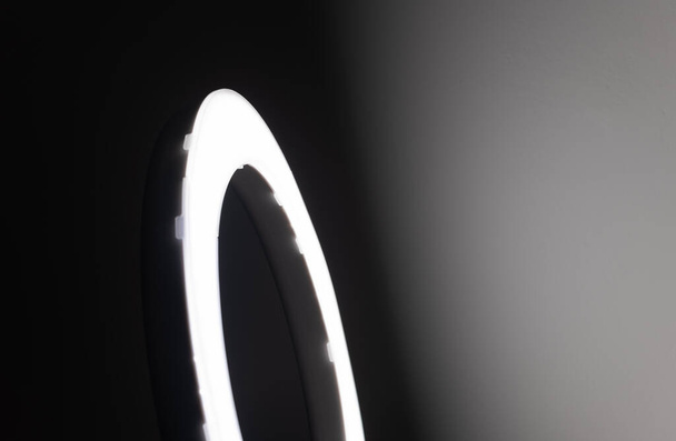 Luz de anillo led grande en una habitación estudio contra las paredes vacías vista lateral y el efecto de pared de degradado de luz muy oscuro a brillante. - Foto, imagen