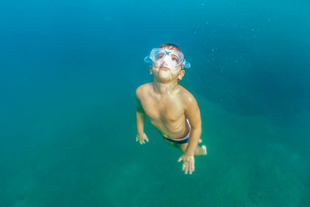 Küçük çocuk okyanusta yüzüyor. - Fotoğraf, Görsel