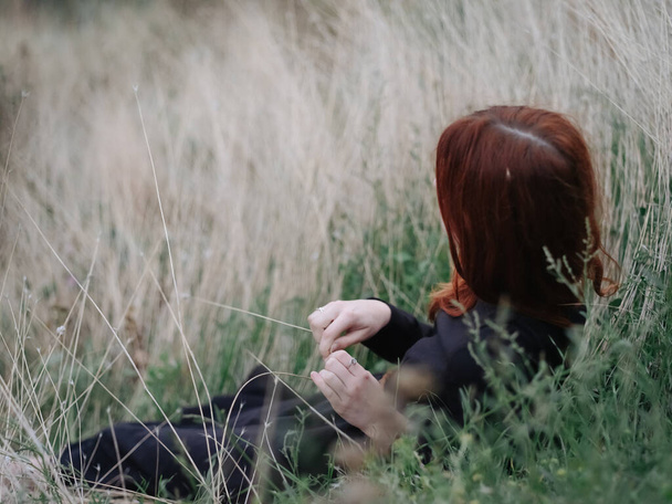 Romantic woman in black dress red hair nature dry grass autumn - Photo, Image