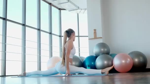 Fitness ragazza in abbigliamento sportivo stretching gambe nel moderno studio di palestra. - Filmati, video