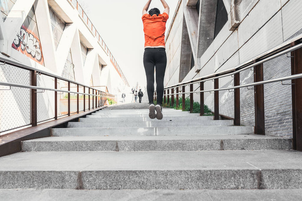 Homme vêtu de vêtements de sport sautant tout en montant quelques escaliers dans la rue - Photo, image