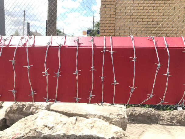 Protective barbed wire on a red background - Photo, Image
