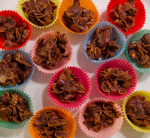 Image plein cadre de gâteaux croustillants au chocolat en flocons de maïs dans des étuis en papier coloré - Photo, image