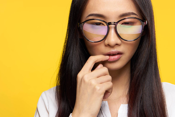 woman asian appearance elegant style glasses hand near face yellow background - Valokuva, kuva