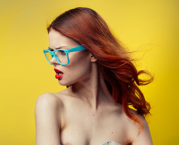 žena v modrých brýlích na žlutém pozadí portrét - Fotografie, Obrázek
