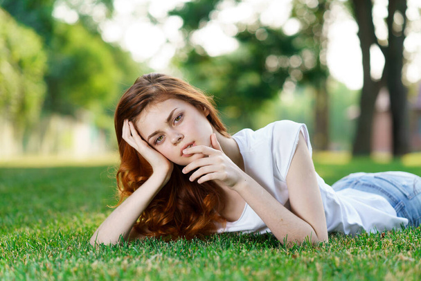 iloinen nainen makaa nurmikolla puistossa ulkona virkistys - Valokuva, kuva