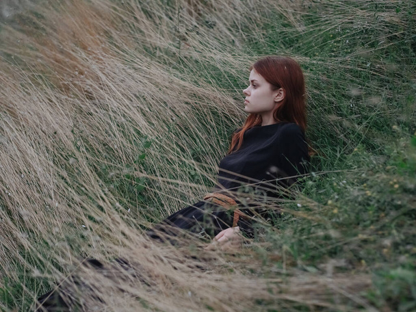Ты женщина в черном платье, идущая по сухой траве в горах к природе - Фото, изображение