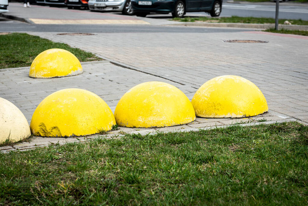 Жовті бетонні сфери на тротуарі, перешкода для паркування автомобілів в неправильному місці
. - Фото, зображення