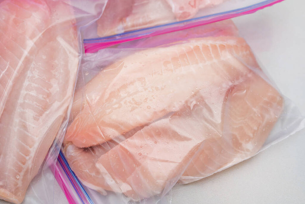 Čerstvé syrové rybí filety v pytlích na zip lock. Tilapia filet na světle mramorovém pozadí, zblízka pohled shora - Fotografie, Obrázek