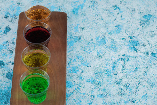 Kleurrijke drankjes in kopjes op een houten schotel - Foto, afbeelding