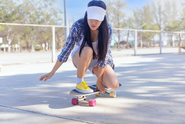 Jovens mulheres asiáticas jogar surf skate board no parque skate rampa ao ar livre na manhã. As mulheres felizes jogam surf board no parque. Esporte conceito de estilo de vida atividade - Foto, Imagem