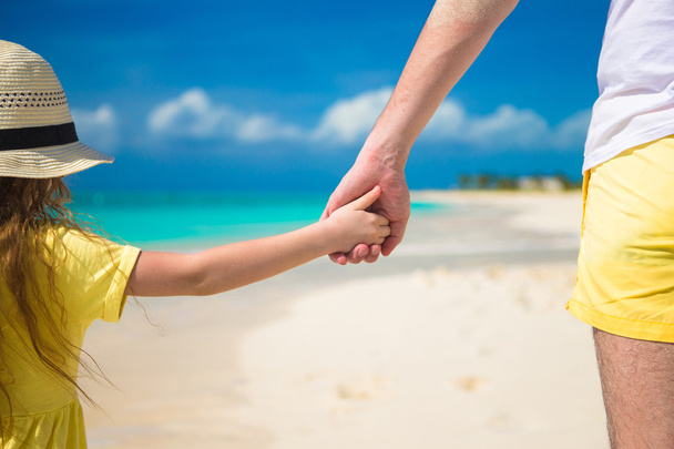Close up of father and little daughter holding each other hands at beach - Photo, Image
