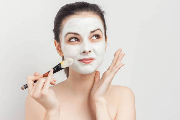 vrouw met blote schouders aanbrengen borstel gezicht masker huidverzorging spa behandelingen - Foto, afbeelding