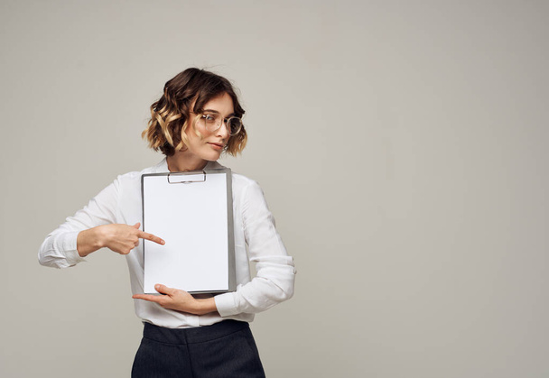 Folder with a white sheet of paper on a gray background in the hands of a woman mockup - Photo, Image