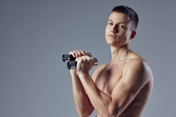sportieve man met halters in handen workout spieren oefening biceps - Foto, afbeelding