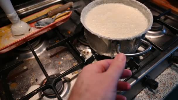家庭での生活のシーン:キッチンでの小さな事故は、一方、ベシャメル調理されていた、それは、ストーブの汚れをこぼした。手で鍋を動かして確認する. - 映像、動画