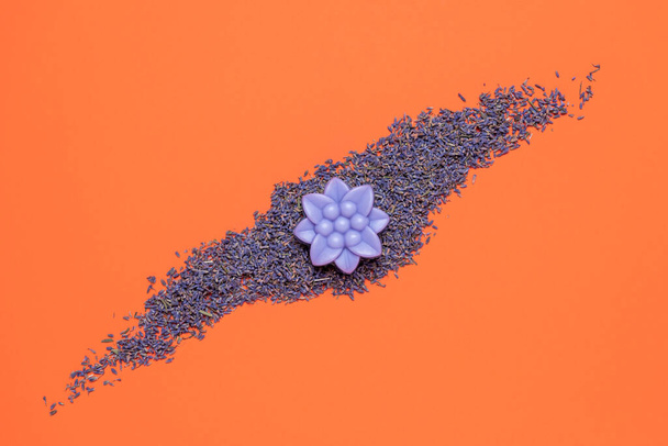 Natural lavender soap in flower shape above view on an orange-colored background. Lavender seeds and soap isolated on a colorful table. - Photo, Image