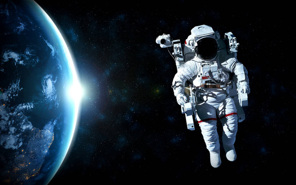 宇宙飛行士は宇宙ステーションで働いている間に宇宙遊泳をします - 写真・画像