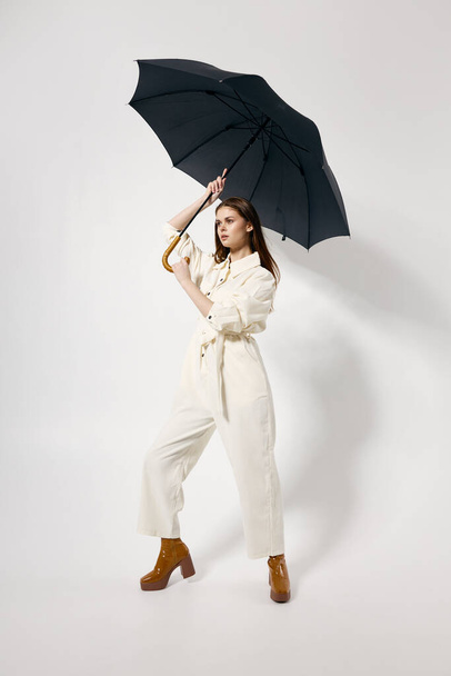woman with an open umbrella over her head in a white suit posing in full growth - Foto, Imagen