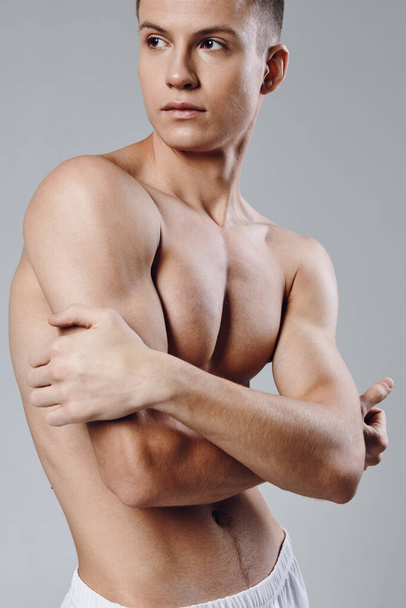 atleta con músculos bombeados prensa culturista fondo gris  - Foto, Imagen