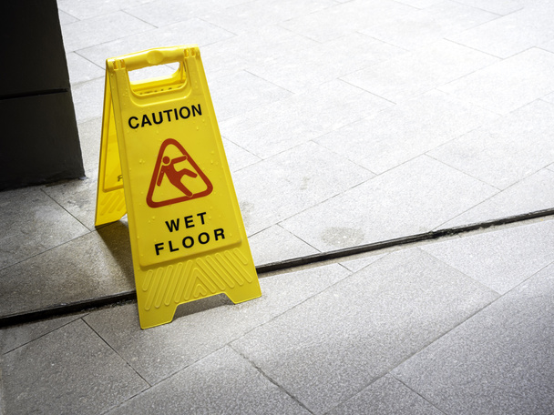 雨が降った後、建物の近くの歩道にぬれた床の注意標識。コピースペースで地面に黄色のプラスチック注意湿った床のサインを警告. - 写真・画像
