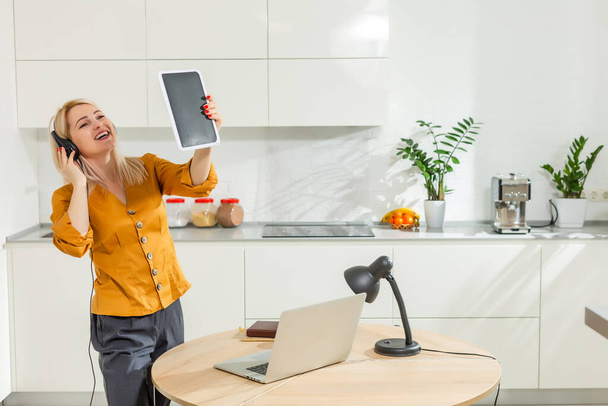 блондинка біла дівчина працює з дому за столом на кухні, використовуючи книгу ручкою стіл зі свічками зайнятий офіс блокує прихований планшет в руці
 - Фото, зображення