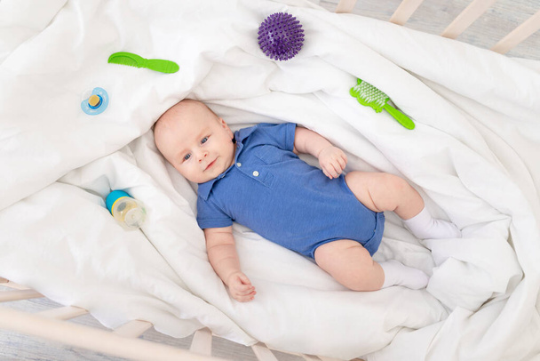 bebé niño en una cuna entre los suministros para bebés, concepto de productos para bebés - Foto, Imagen