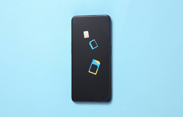 Karta SIM ze smartfonem na niebieskim tle - Zdjęcie, obraz