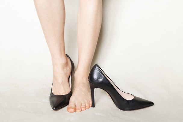 joven chica en negro punta puntiaguda zapatos de tacón alto se encuentra en una alfombra blanca en casa - Foto, imagen