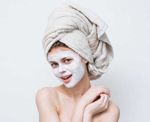 mooie vrouw met blote schouders gezicht crème handdoek op hoofd schone huid - Foto, afbeelding