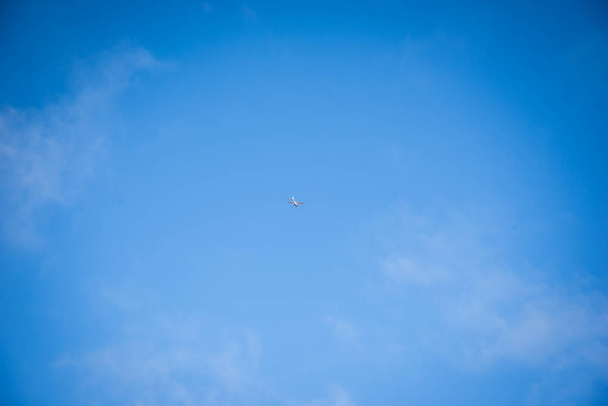 Weißes Flugzeug am blauen Himmel. Leicht sichtbare weiße Kumuluswolken. - Foto, Bild