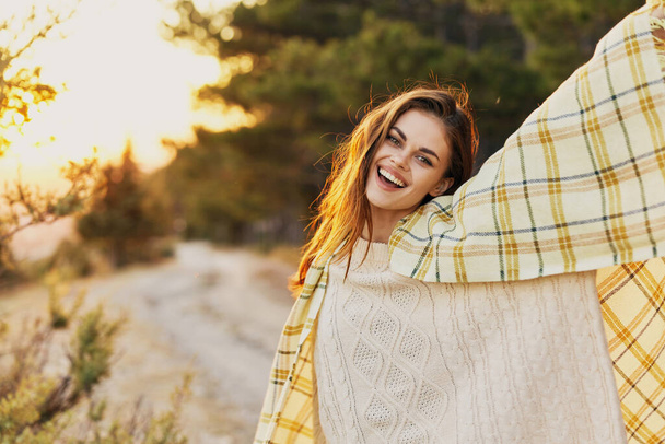 夕暮れ時に彼女の肩に毛布と針葉樹林の近くの幸せな女性 - 写真・画像