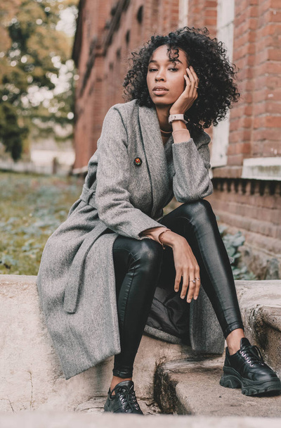 Portrait d'une femme afro-américaine assise sur les marches près du bâtiment et posant - Photo, image