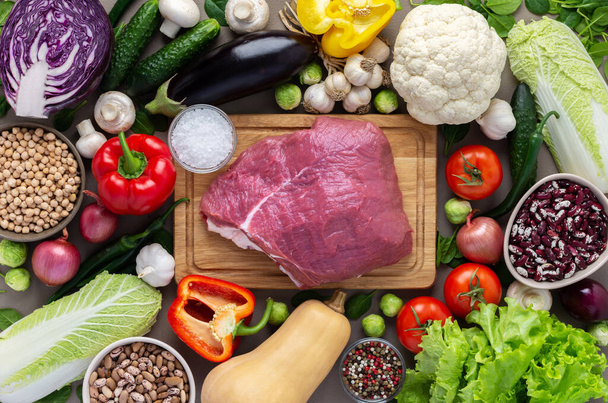 Φρέσκα βιολογικά λαχανικά αγροκτήματος, υγιεινά τρόφιμα, λαχανικά και μανιτάρια, superfoods και φασόλια γύρω από το τραπέζι με ένα μεγάλο φρέσκο κομμάτι φιλέτο βοδινού, top view - Φωτογραφία, εικόνα
