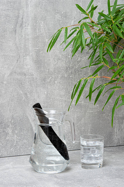 Bamboo charcoal water filter stick, green leaf and glass of water. Natural bamboo charcoal is a powerful purifier which refreshes tap water - Photo, Image