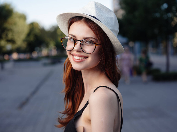 beautiful woman in hat outdoors in nature near buildings - Photo, Image