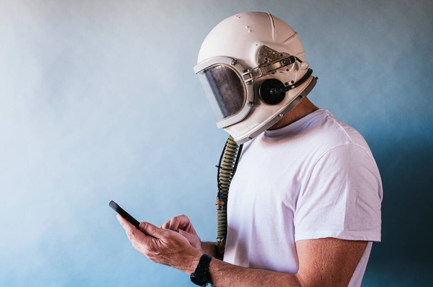 Mann mit Astronautenhelm nutzt Smartphone - Foto, Bild